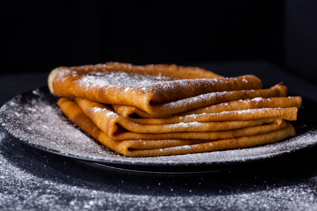 Stack,Of,Crepes,With,Powdered,Sugar,On,Dark,Background.,Pancakes 